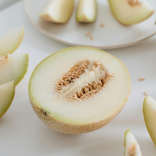 Sliced cantaloupe showcasing fresh seeds on a clean white surface, ideal for healthy eating themes.