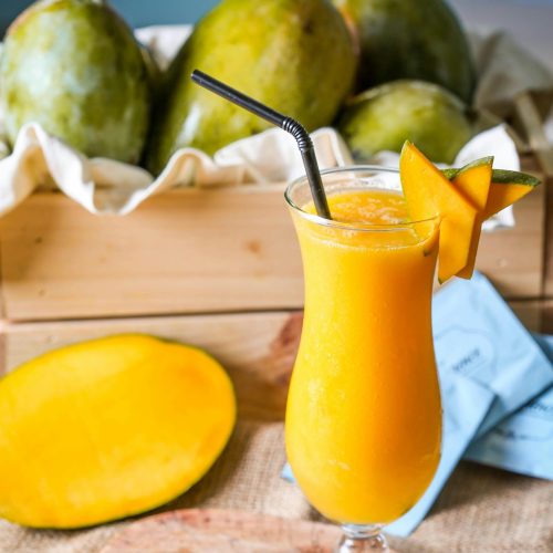 A refreshing glass of mango juice garnished with mango slices, perfect for summer.