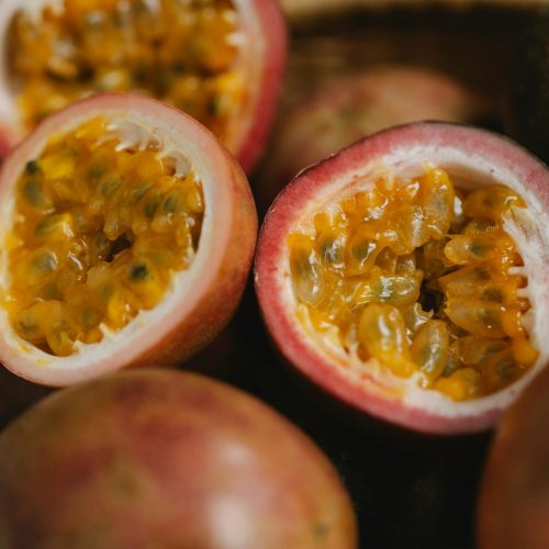 Close-up of fresh halved passion fruit revealing its vibrant pulp in a rustic basket.